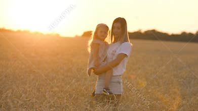 Beautiful young mother and her daughter having fun at the wheat field