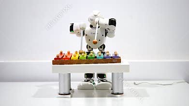 A small robot plays on a xylophone close up