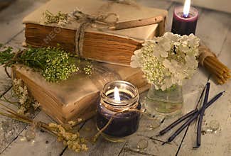 Old books with black candles and healing herbs and flowers