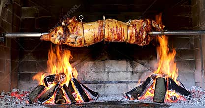 Pig spinning on spit - cooking piglet in firewood grill