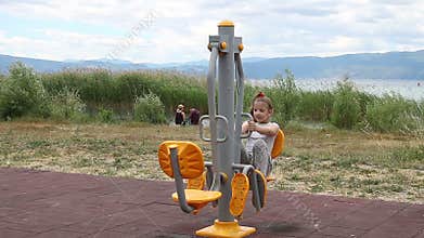 Little girl outdoor exercise on fitness equipment
