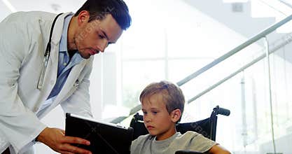 Doctor showing digital tablet to disable boy