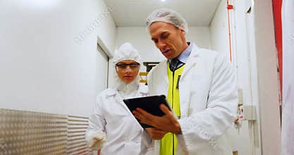 Technicians using digital tablet while walking in corridor