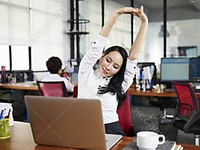 Asian business woman stretching arms in office