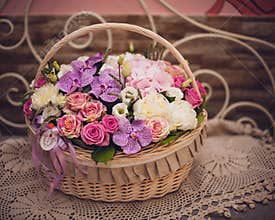 Beautiful bouquet of pink flowers in basket on decorated table