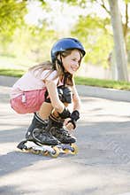 Young girl outdoors on i line skates smiling