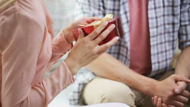 Man giving woman red gift box with perl jewelry