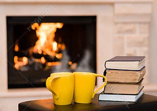 Two cups of coffee with books on the background of the fireplace