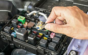 Auto mechanic checking a car fuse