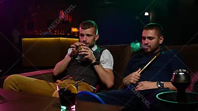 Friends smoke from shisha pipei n the lounge
