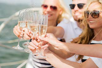 Happy friends with glasses of champagne on yacht