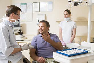 Dentist and assistant in exam room with man