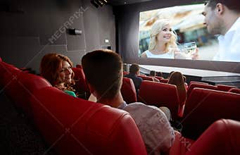 Happy couple watching movie and talking in theater