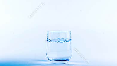 Water movement pouring in glass on white background blue tint effect, nutrition and diet concept