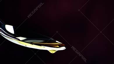 Extra virgin olive oil over a spoon with drops isolated on dark wood background