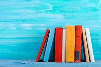 Stack of colorful books, grungy blue background, free copy space