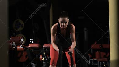 Endurance. Muscular woman exercising with rope in crossfit gym