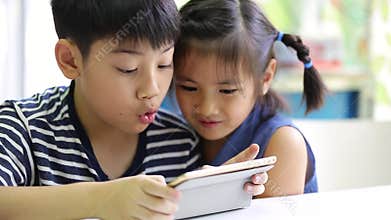 Little asian boy with tablet computer and little girl playing together