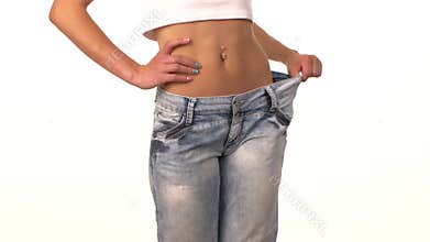 Slim girl in big jeans, showing her lose weight