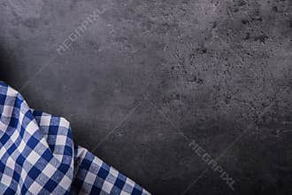 Top view of checkered kitchen tablecloth on granite - concrete - stone background. Free space for your text or products