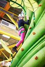 Girl athlete climbing on artifical green tree