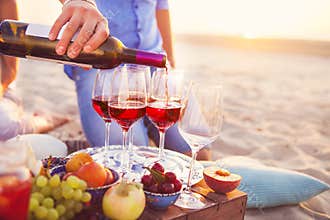 Happy friends having red wine on the beach. Sunset beach party