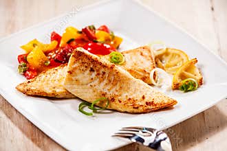 Two tilapia fish fillets on white plate