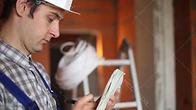 Builder with a notebook on the construction site closeup