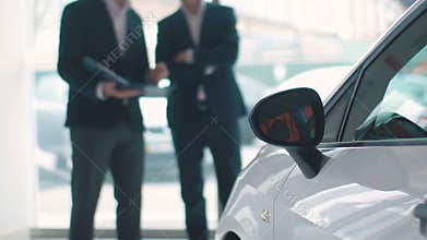 Salesman talking with customer in car dealership