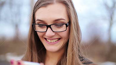 Happy woman using a smart phone in the street with an unfocused background