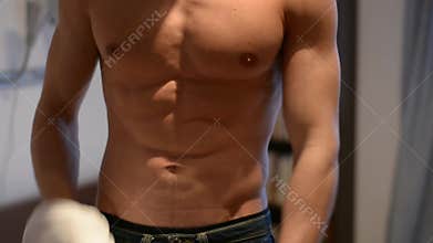 Young fit man opening sweater on naked muscular torso