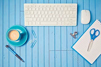 Office desk flat lay with keyboard, coffee cup and notebook. View from above.