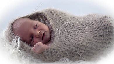 Baby lies in woollen cover with it's hands stretched