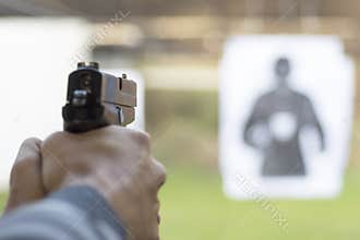 Man Firing Pistol at Target in Shooting Range
