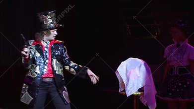 Wizard and assistant are participating in the show. Illusionist shoots a gun in a flower bouquet disappears.