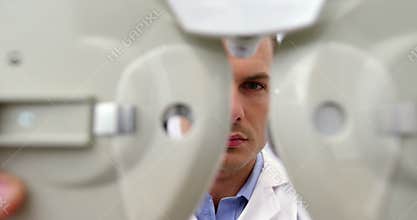Attentive optometrist adjusting phoropter