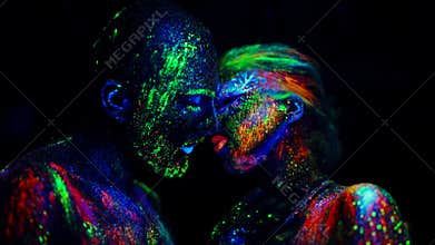 Couple in love painted fluorescent powder kiss under ultraviolet light.