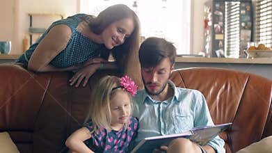 Happy family. young father and his little blond daughter are reading a story on leather sofa in the dining room. 4K