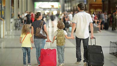 Happy family with little girl and boy going on railway station, mother father and the kids walk through the airport with