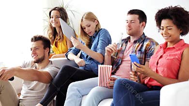 Friends with gadgets and beer watching tv at home