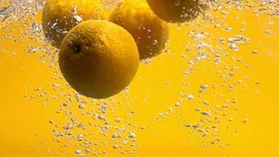 Whole oranges falling into water iin slow motion