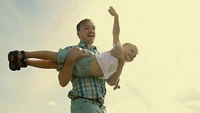 Close-up of father and son playing together. Young father rotates his son in hands