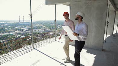 Two male builders walking through the building under construction
