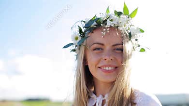 Smiling young woman in wreath of flowers outdoors