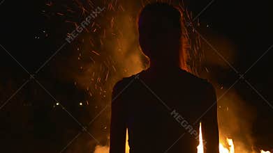 Silhouette of a young woman on in front of fire