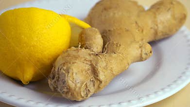 Ginger and sliced lemon rotating on a round white plate