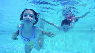 Underwater shot of two kids diving in a swimming pool