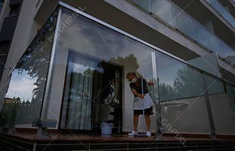 A cleaning worker wearing protective mask scrub the floor of a hotel balcony room