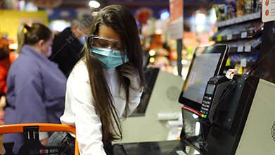 A young woman scans products in a mask and gloves.