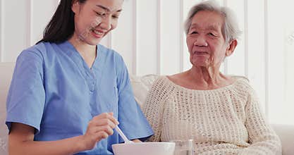 Asian elderly woman being fed by a nurse by volunteer with happy emotion.